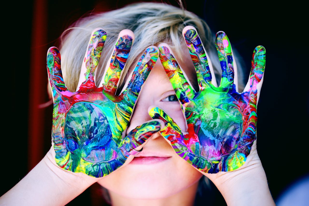 Home Vibrant close-up of a childs hands covered in colorful paint, expressing creativity and fun.